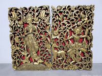 Front view of two Asian figure wall plaques with detailed gold carvings on red background showing standing and seated figures with floral motifs.