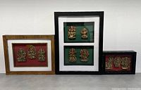 Three shadow framed displays of Indian gods showing different sized frames and arrangements of brass-colored figurines.