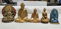 Front view of five sitting Buddha statues displaying variety of styles and colors