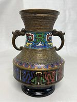 Front view of antique Japanese cloisonné enamel brass vase showing multi-color abstract geometric patterns and two animal shaped handles.