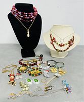 Full display of all jewelry including necklaces on busts and loose bracelets, brooches, earrings arranged on table surface.