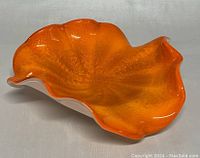 Orange and white hand blown glass bowl showing waved, ruffled edges and textured bubble interior