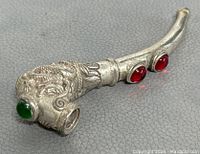 Front angled view of the silver plated pipe showing detailed dragon design and green gemstone on the bowl.