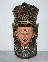 Front view of one Balinese wood wall sculpture showing hand-carved details and colorful paint.