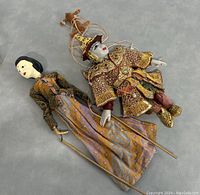 Two puppets laid flat showing their full bodies and detailed costumes.