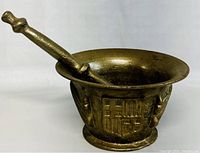 View of brass mortar showing embossed shield pattern and pestle inside