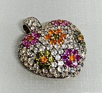 Close-up of front face of the heart-shaped pendant showing colorful rhinestone clusters in purple, orange, green and white on a silver setting.