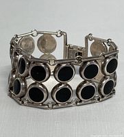 Close-up side angle showing two rows of round black onyx stones set in sterling silver with linked chain and clasp details.