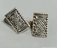 Close-up front view of a pair of rectangular sterling silver cufflinks with raised knot design and beaded edges.