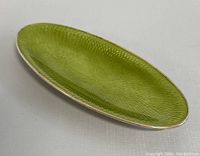 Front angle photo showing green guilloche enamel surface and silver rim of oval trinket dish.