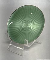 Front view of small round dish showing green guilloche enamel with radiant pattern and silver rim