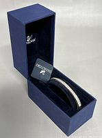 Silver-tone Swarovski bracelet displayed inside original blue velvet-lined Swarovski box, showing embedded crystals and brand tag.
