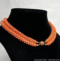 Front view on black bust showing six twisted strands of coral beads.