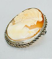 Front angled view of vintage 800 silver cameo brooch showing intricate carved female profile with floral details and silver twisted rope frame.
