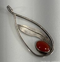 Front view of vintage sterling silver teardrop pendant with amber stone set alongside a silver leaf design.