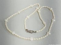 16 inch freshwater pearl necklace laid flat showing small and irregular pearls with a lobster claw clasp.