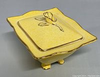 Top angle of the yellow lidded candy bowl showing the gold-rimmed rectangular lid with rose-shaped handle and floral detailing.