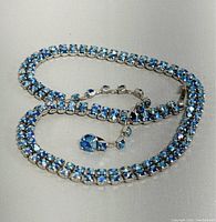 Vintage Sherman choker necklace laid out showing blue rhinestones in silver-tone setting with fold-over clasp and safety chain.
