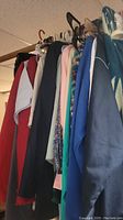Photo showing the assortment of hanging clothing including coats, jackets, and blouses in various colors and fabrics.
