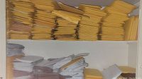 Shelves filled with large stacks of folded yellow padded mailers and stacks of white poly mailers below.