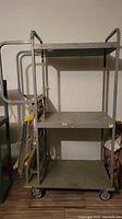 Front view of large steel shelf with three shelves and attached wheeled ladder.