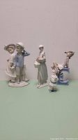Four Lladro porcelain figurines together on surface against plain background.