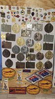 Full display of all medals, pins, and patches arranged on a plain surface, showing the variety and quantity in the lot.