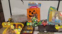 Photo showing pinball game, jar of marbles in plastic Halloween bag, and yellow wind-up ducks on top of decorative tin boxes.