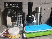 Photo showing 41-piece Gourmet Traditions kitchen set box and some items including Yonanas machine, thermos, ice trays, and smoke detector.