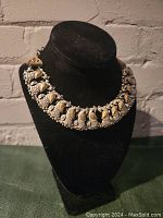 Full view of Persian style necklace on black display bust showing metal bird motifs and gold-silver finish