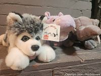 Photo of three plush stuffed animals, front view showing husky, hippopotamus, and elephant on a shelf.