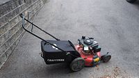 Full view of Craftsman gas-powered lawn mower with grass catcher bag on the side, showing handle and wheels.