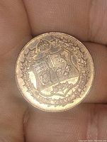 Front side of copper coin medallion showing crowned royal shield and wreath design.