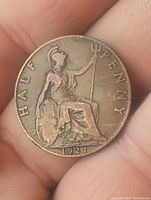 Front side of 1921 English half penny coin showing Britannia with trident and shield, date at bottom, and 'HALF PENNY' inscription.
