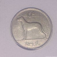 Obverse side of 1928 Irish 6 Pence coin showing the Irish dog figure, denomination 6d and word 'Reul'.