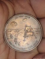 Obverse side of the medallion showing lunar module, astronauts, Earth in background, and commemorative text.