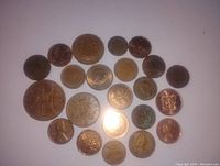 Photo showing 23 different copper coins arranged on a flat surface in two different arrangements. Coins vary in size and design, some showing patina and wear.