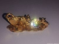 Front angled view showing two gold plated cats playing with a rainbow-colored reflective ball on a textured base.