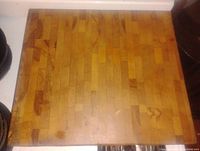 Top-down view of solid maple butcher block cutting board showing the entire surface with discolorations and wear marks.