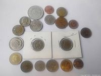 Top down photo of 20 mixed coins arranged in a semicircle plus two coins in white cardboard 2x2 holders showing front details.