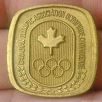 Front side showing Canadian Olympic Association emblem with maple leaf and Olympic rings, surrounded by text and laurel motif.