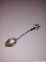 Close-up photo showing front side of the antique hand made sterling silver spoon with twisted handle and oval bowl.
