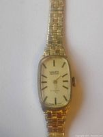 Close-up photo of the watch face showing the Gruen Precision branding and mechanical winding indication, gold-tone rectangular watch face with black markers and hands.