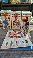 Three boxed Dallas Mavericks bobbleheads in front of yearbook