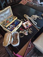 Overview of assorted jewelry spread on table with two cases and loose necklaces visible