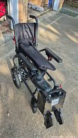 Full view of folded electric wheelchair showing joystick, armrests, footrests