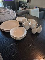 Stacked bowls, plates, mugs, shakers, and quilted storage bag on table