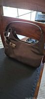 Front view of brown Salvatore Ferragamo small shoulder bag on dust bag