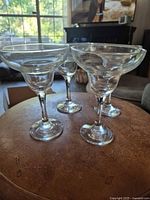 Four clear margarita glasses on ottoman, full view