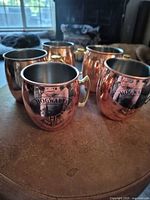 Front view of five copper mugs showing two with Hogwarts crest